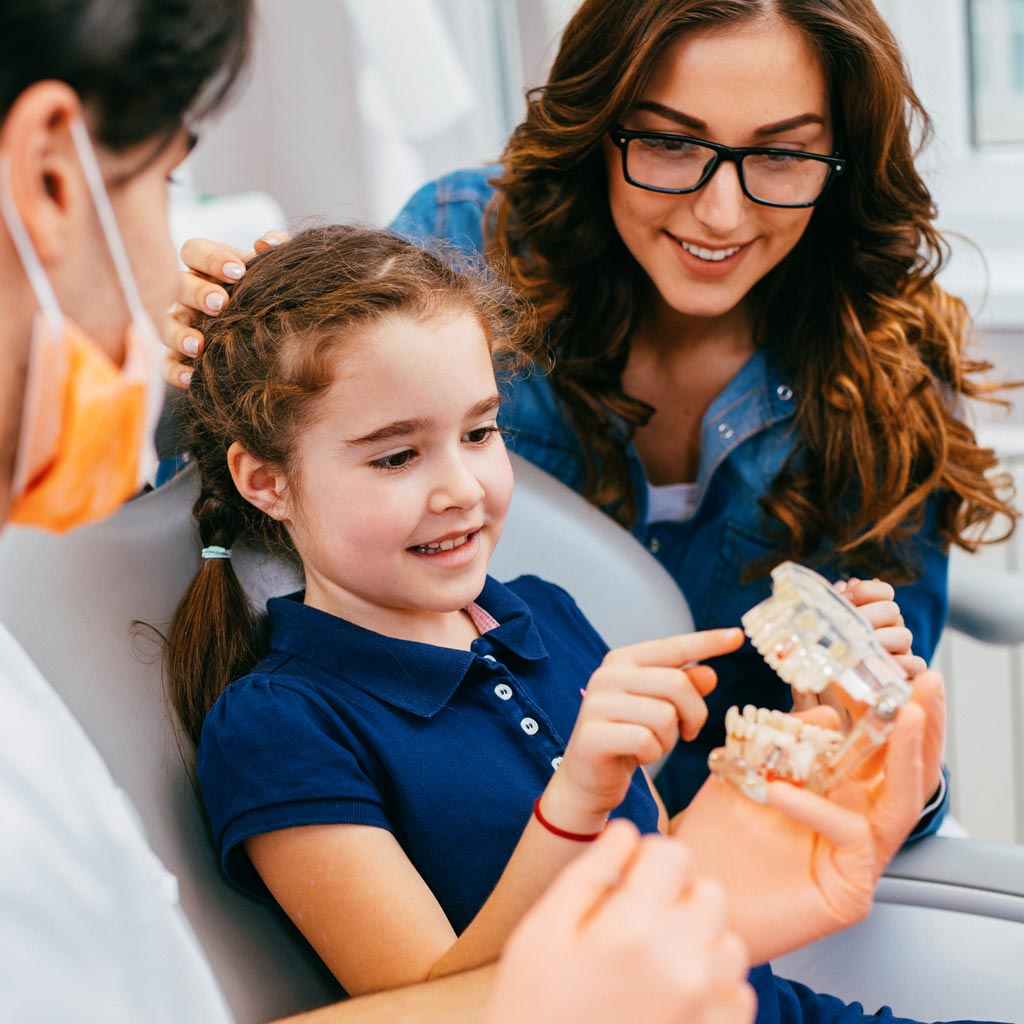 Smiling mom and daughter in dental chair