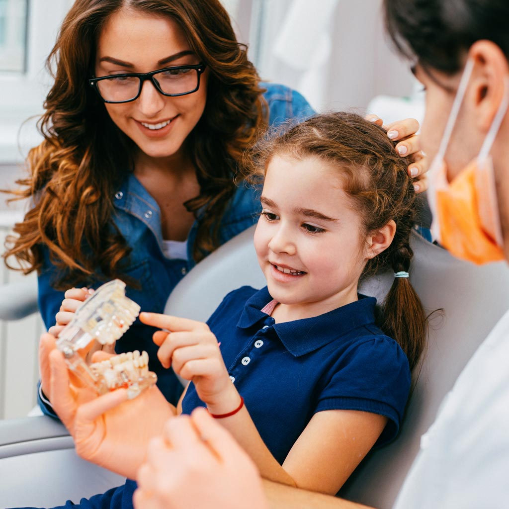Smiling mom and daughter in dental chair
