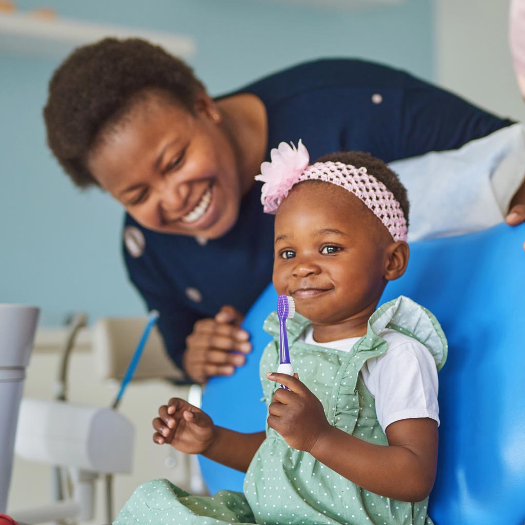 Smiling mom and daughter in dental chair